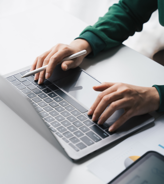 Two hands typing on a sliver laptop. 