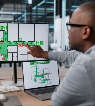 Two professionals look at fire escape routes on a computer screen.